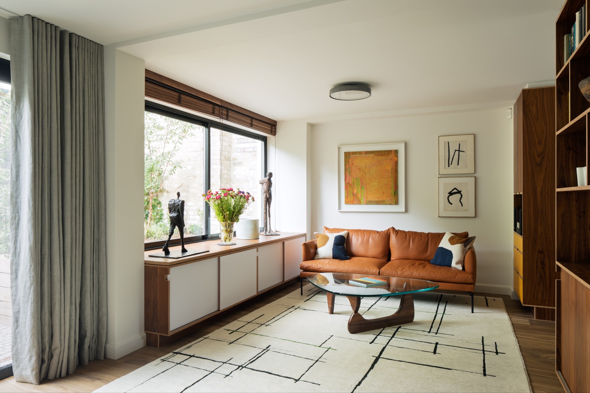 Fitted walnut and white plywood sideboard running below a living room window