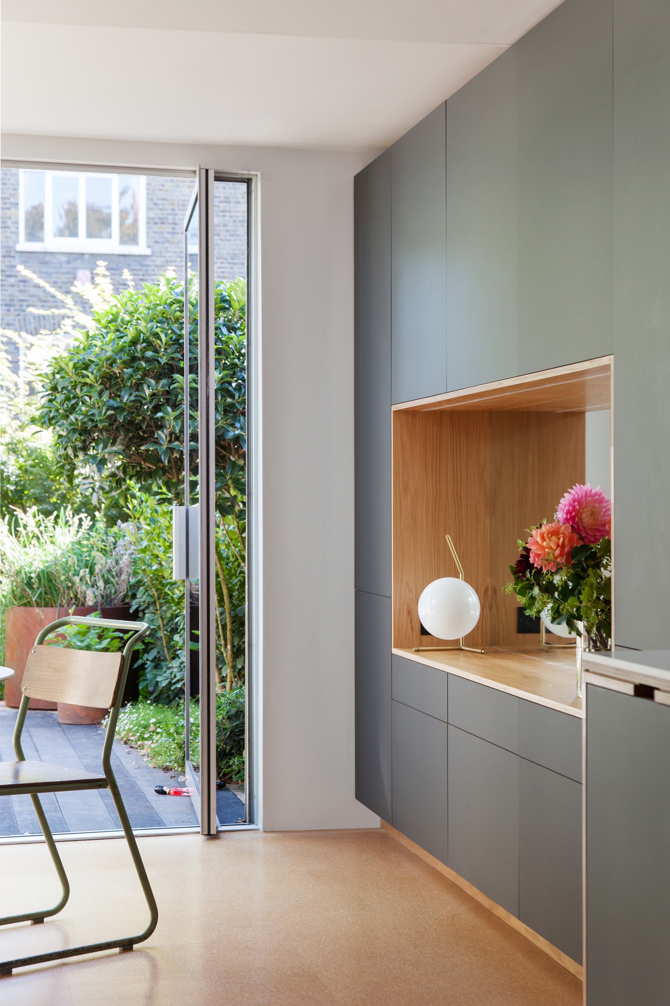 Looking out to a lush garden past black door plywood storage