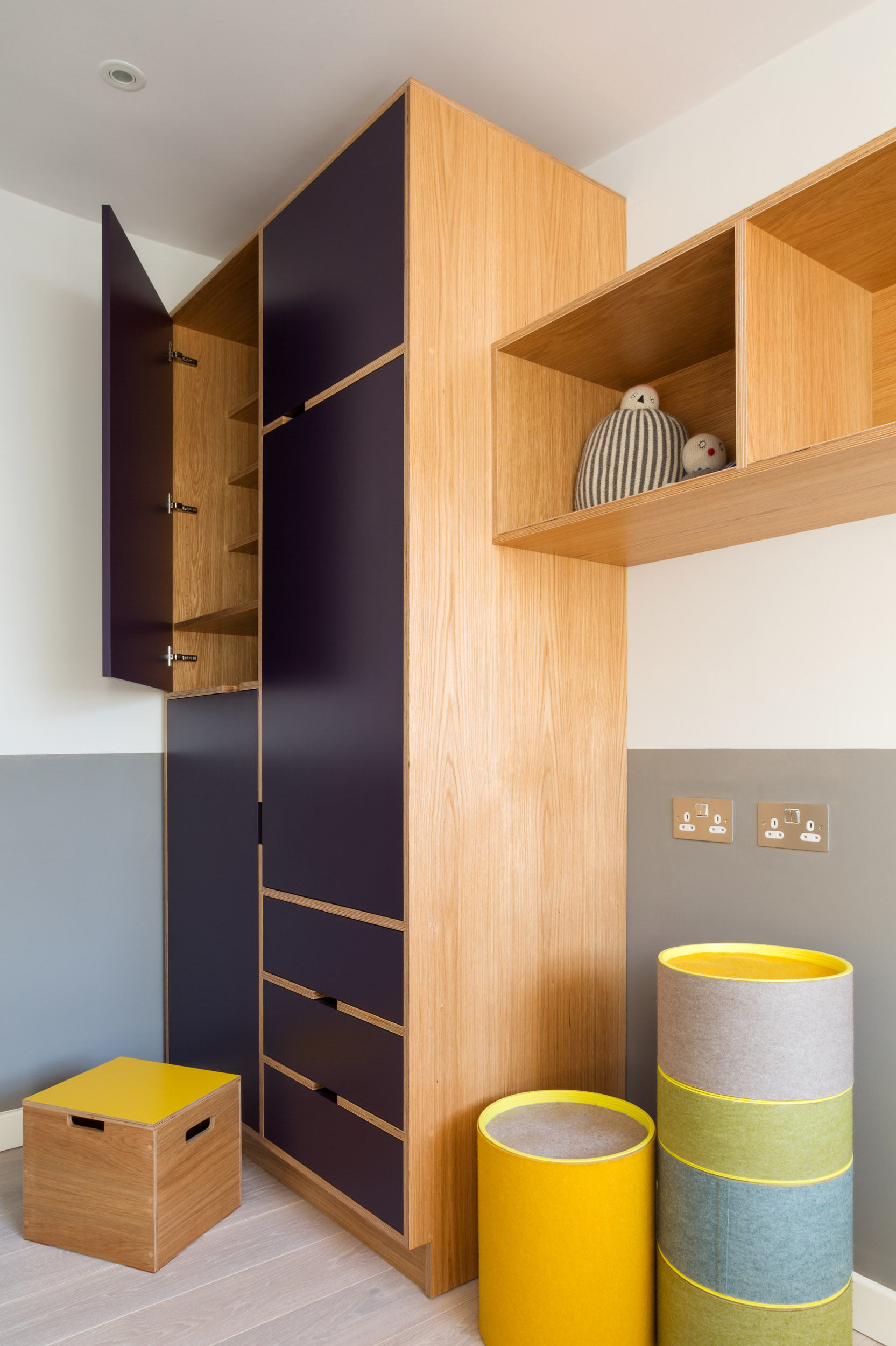 Bespoke plywood children's wardrobe in oak and aubergine with open oak-lined shelving and drawers.