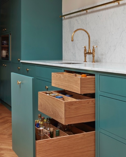 Deep green shaker-style plywood kitchen with oak-lined drawers, marble worktop and aged-brass bridge tap in a period Islington apartment