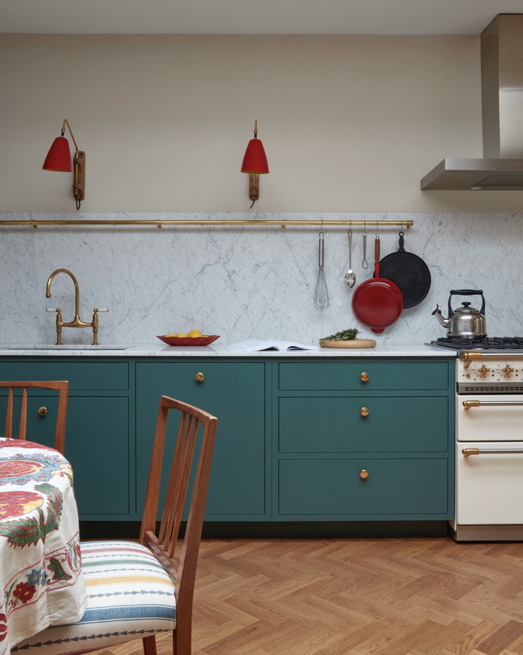 Deep green shaker-style kitchen in an Islington flat, with a white marble worktop and splashback, a brass utensil rail and a cream Lacanche range.