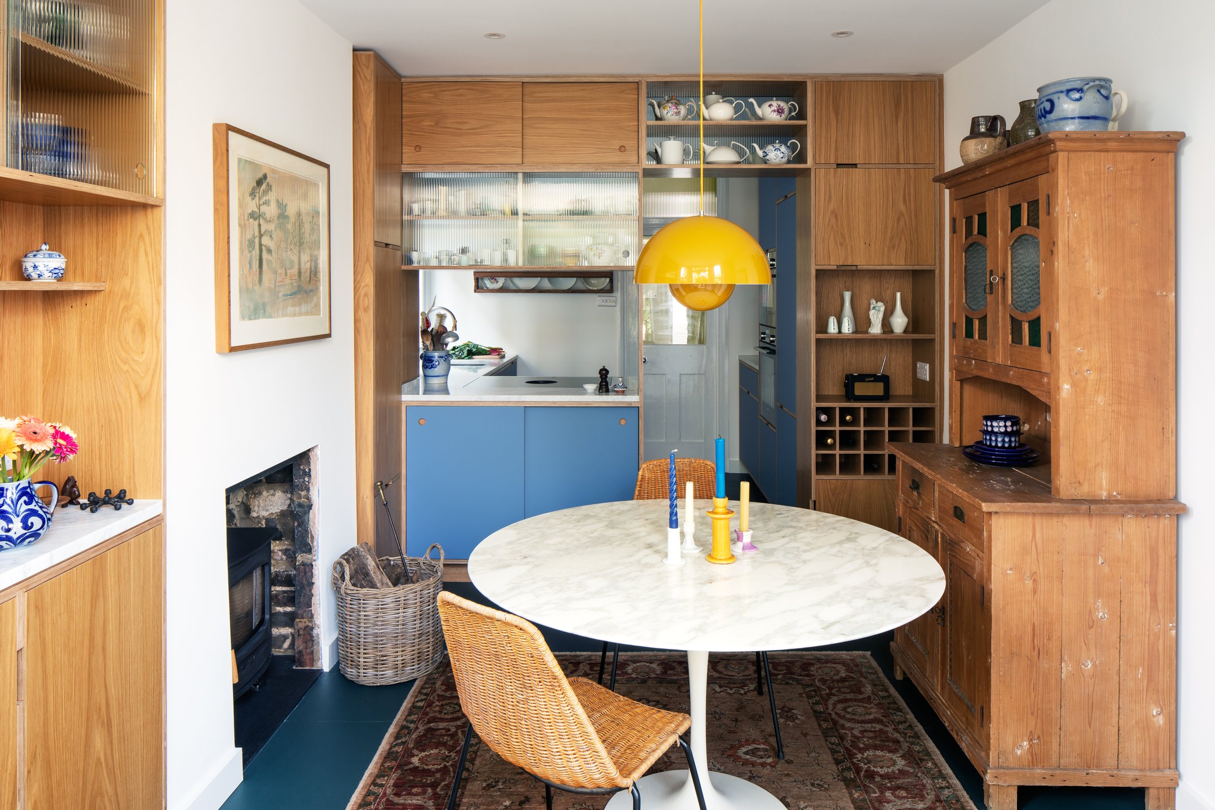 Dining room with marble tulip table, rattan chair and antique pine dresser in front of a bespoke kitchen screen