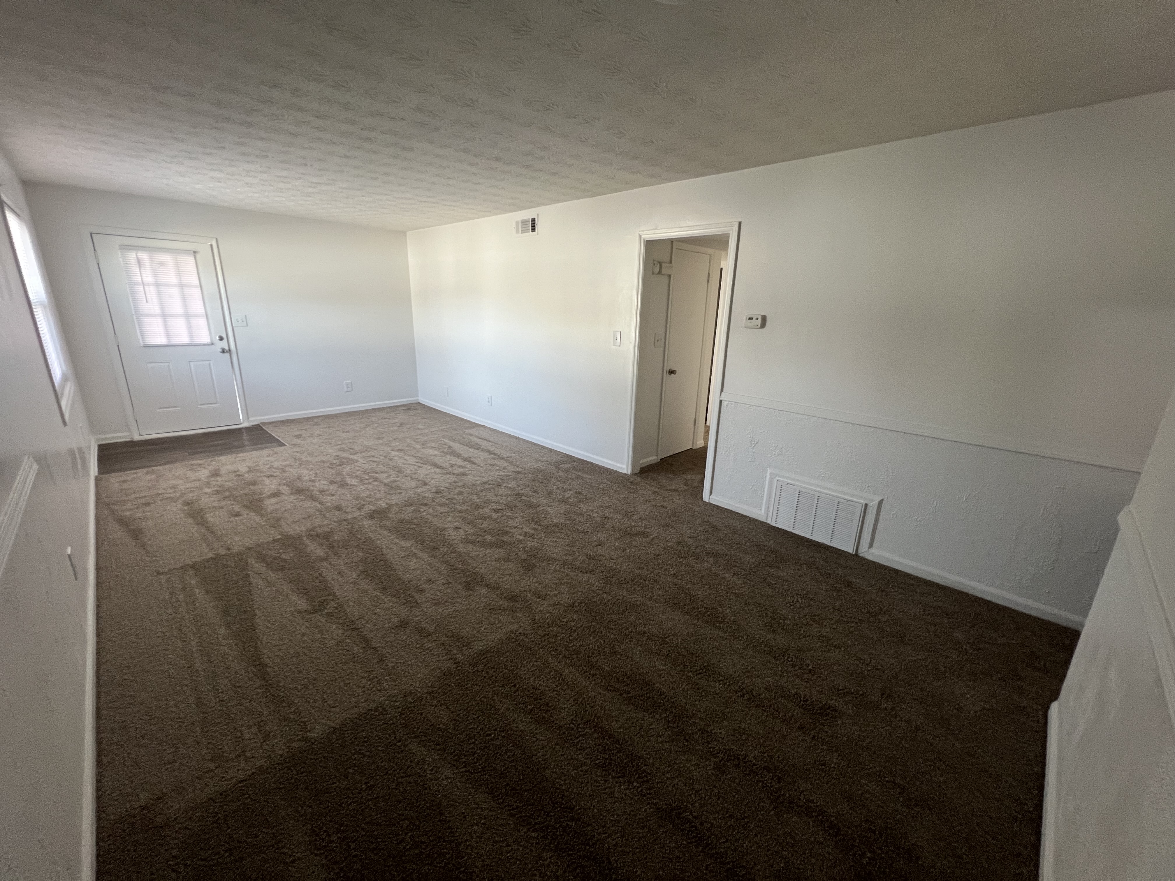 Unfurnished Living Area with large windows and carpet