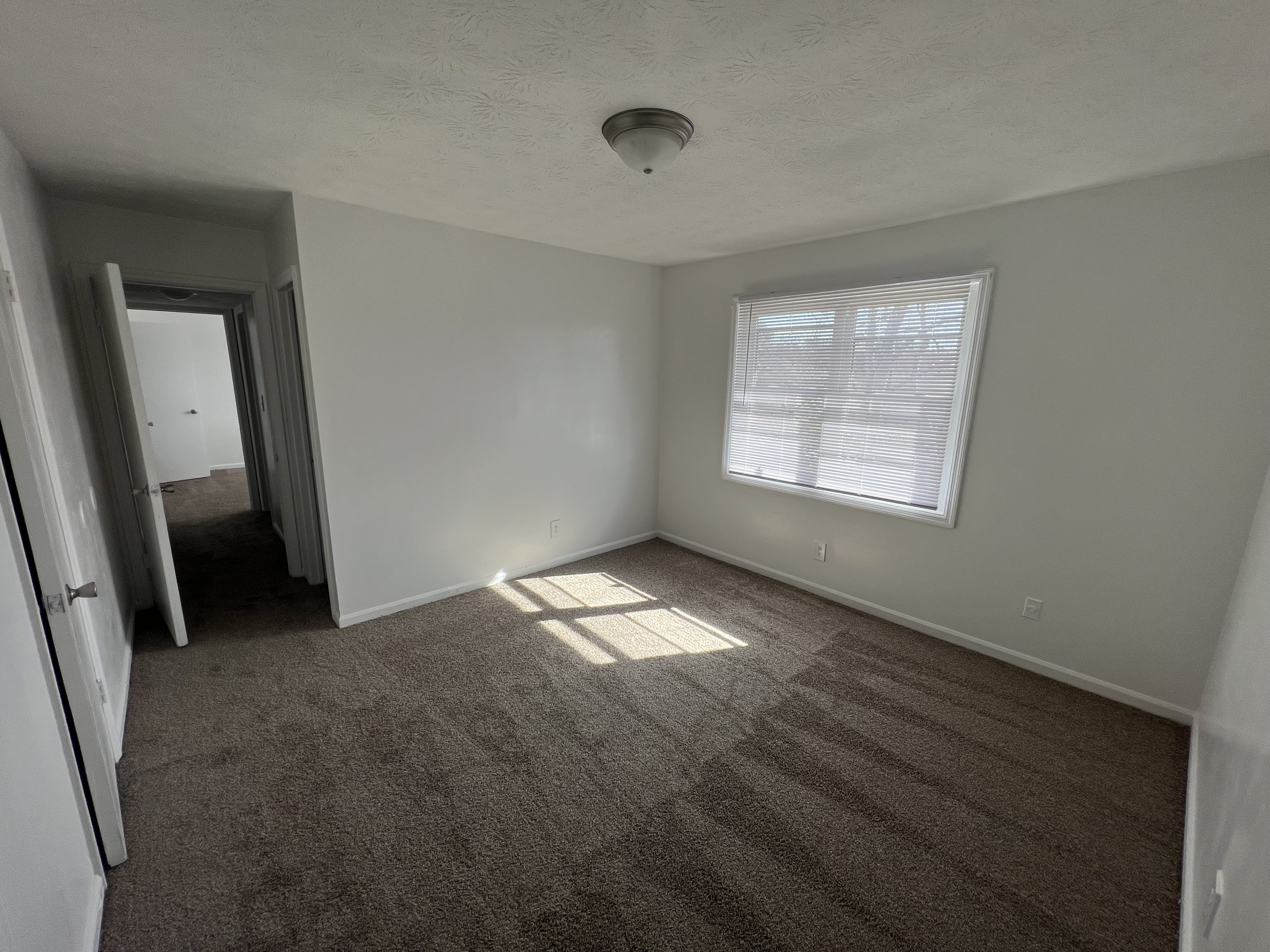 Unfurnished bedroom with window and view of hallway