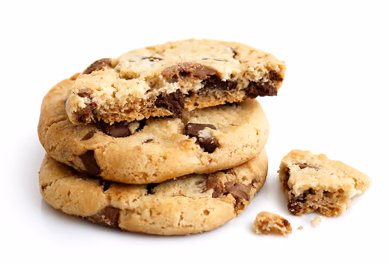 Stack of three chocolate chip cookies with chocolate chunks, one cookie partially broken with a bite taken out and crumbs next to it on a white background.