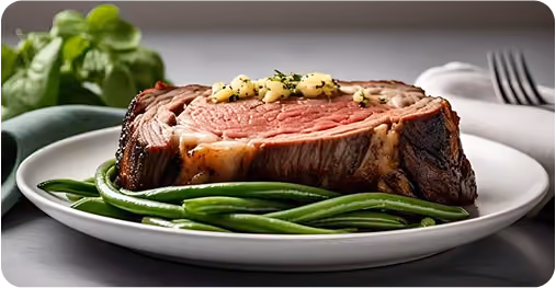Juicy medium-rare steak topped with herb butter served with fresh green beans on a white plate, garnished with basil leaves in the background.