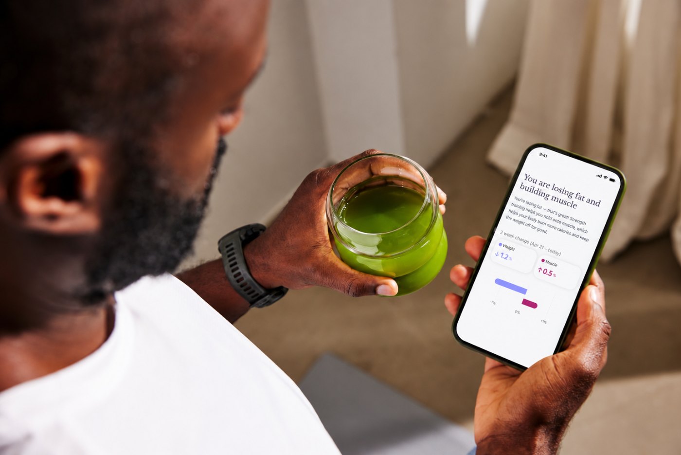 Twin member checking the Twin app while holding a green smoothie