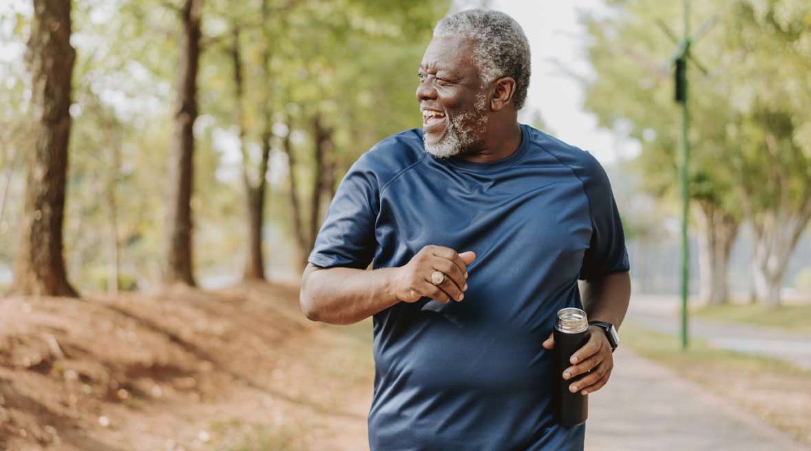 Smiling man jogging outdoors with a water bottle