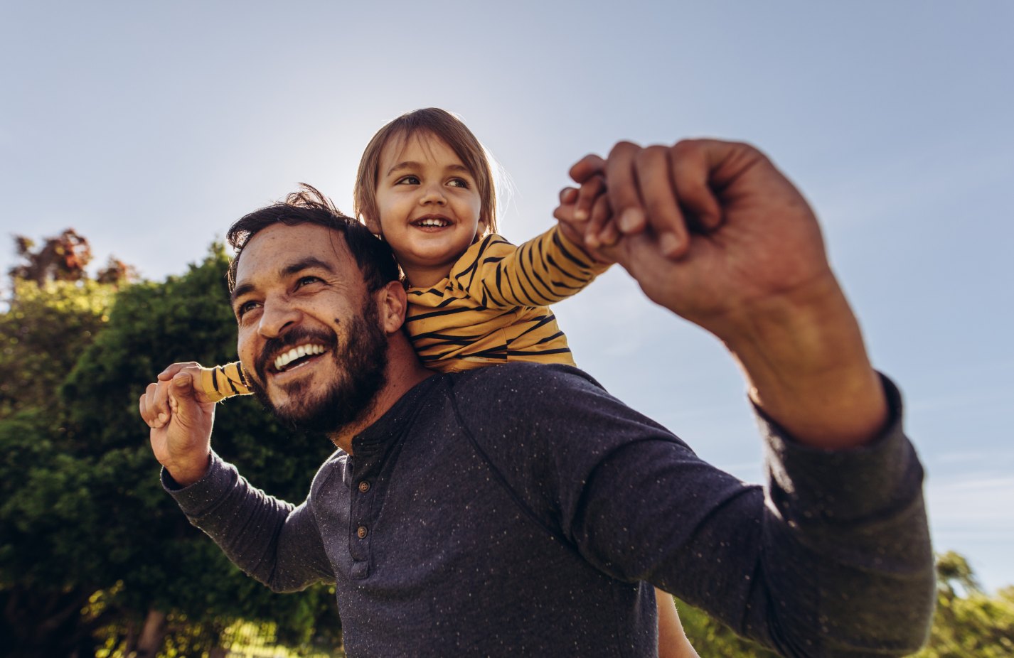 Smiling father carrying his daughter on his shoulders outdoors