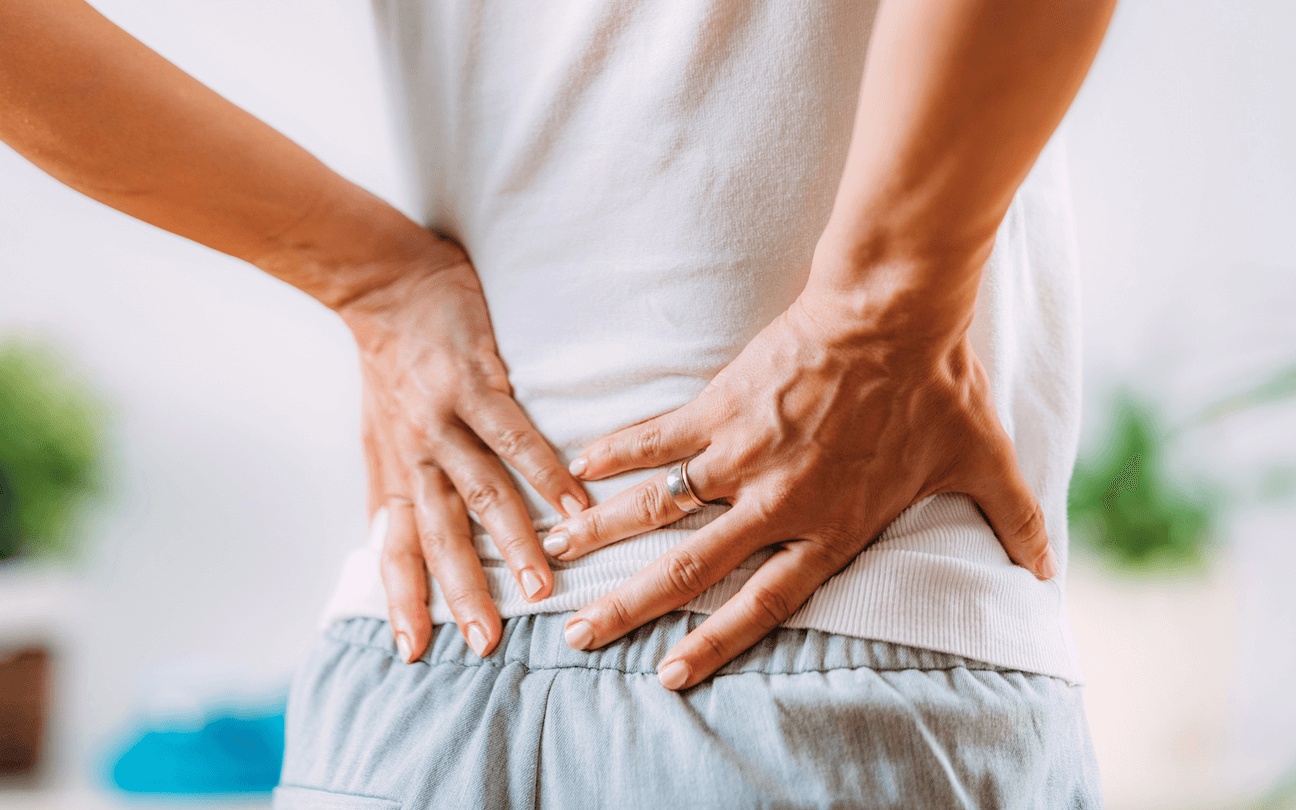 Person holding their lower back in pain, showing signs of sciatica, used to illustrate symptoms and treatment options from the best doctor for sciatica relief in Riverside.