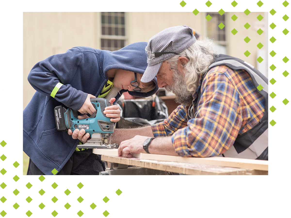 Boy being taught how to use a saw