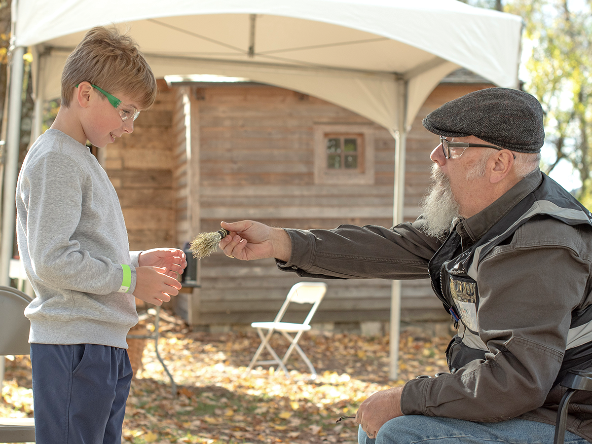 Man teaching child broom making.