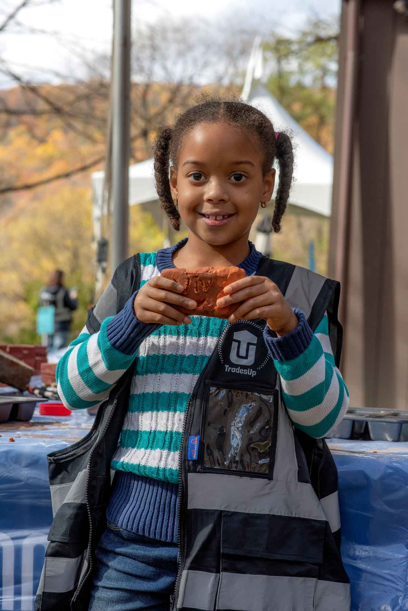 Girl holding brick she made.