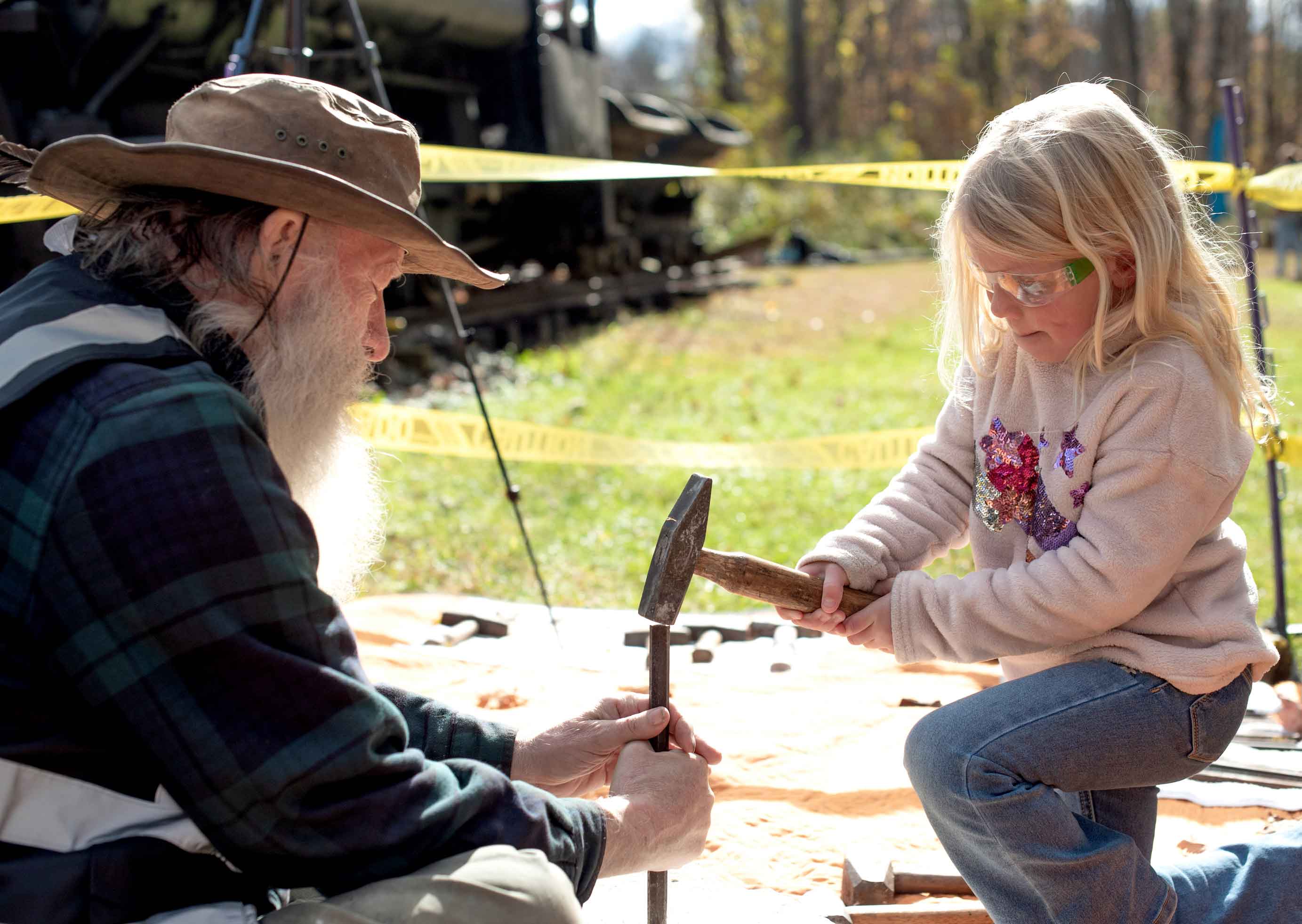 Man showing girl how to hammer.
