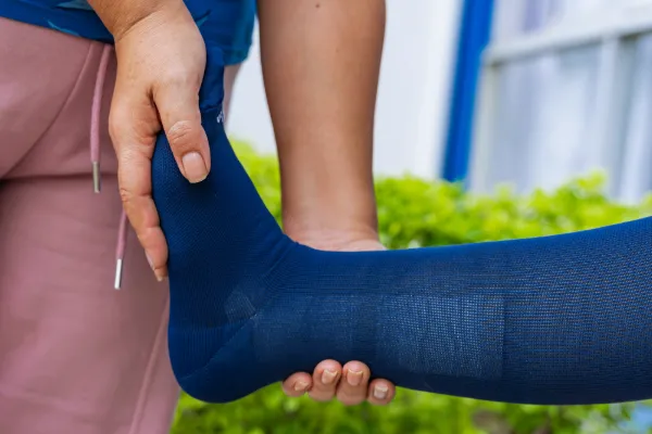 Caregiver helping a loved one put on a compression stocking