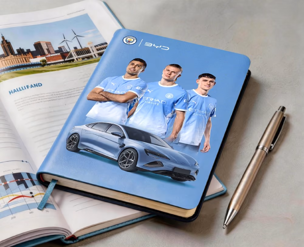 Blaues Notizbuch mit Aufdruck von Fußballern und einem BYD SEAL