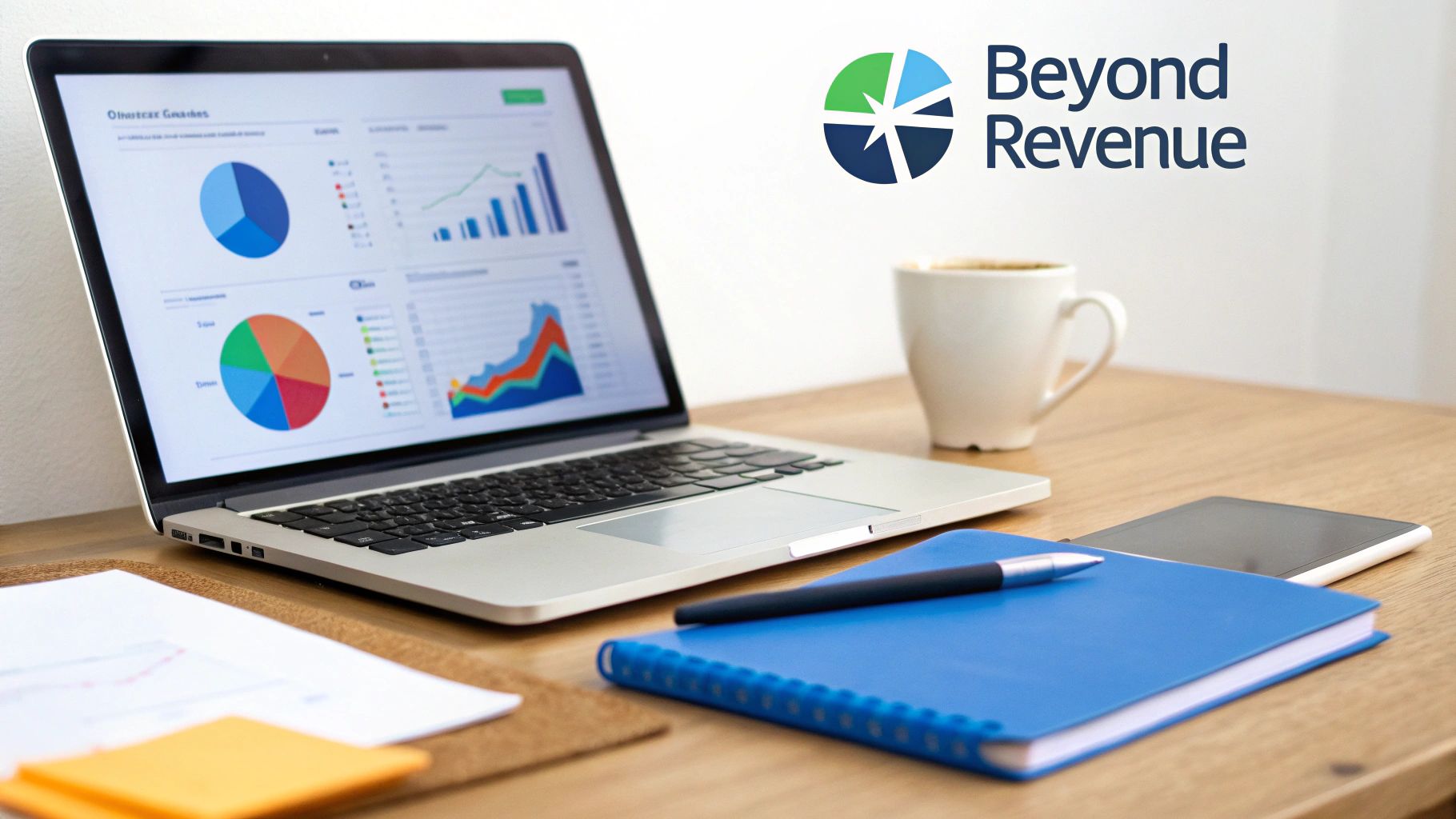 A laptop screen displays business analytics with charts and graphs on a wooden desk alongside office supplies.