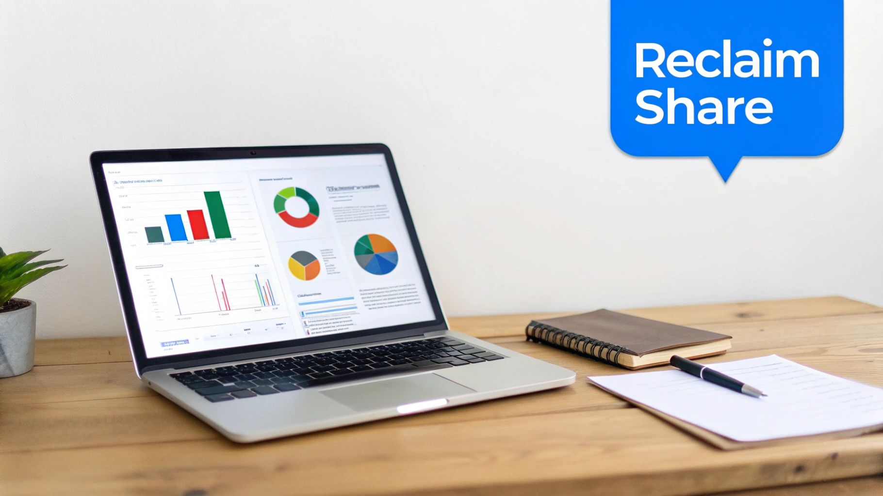 A laptop on a wooden desk displays data charts, with a notebook, pen, and document nearby.