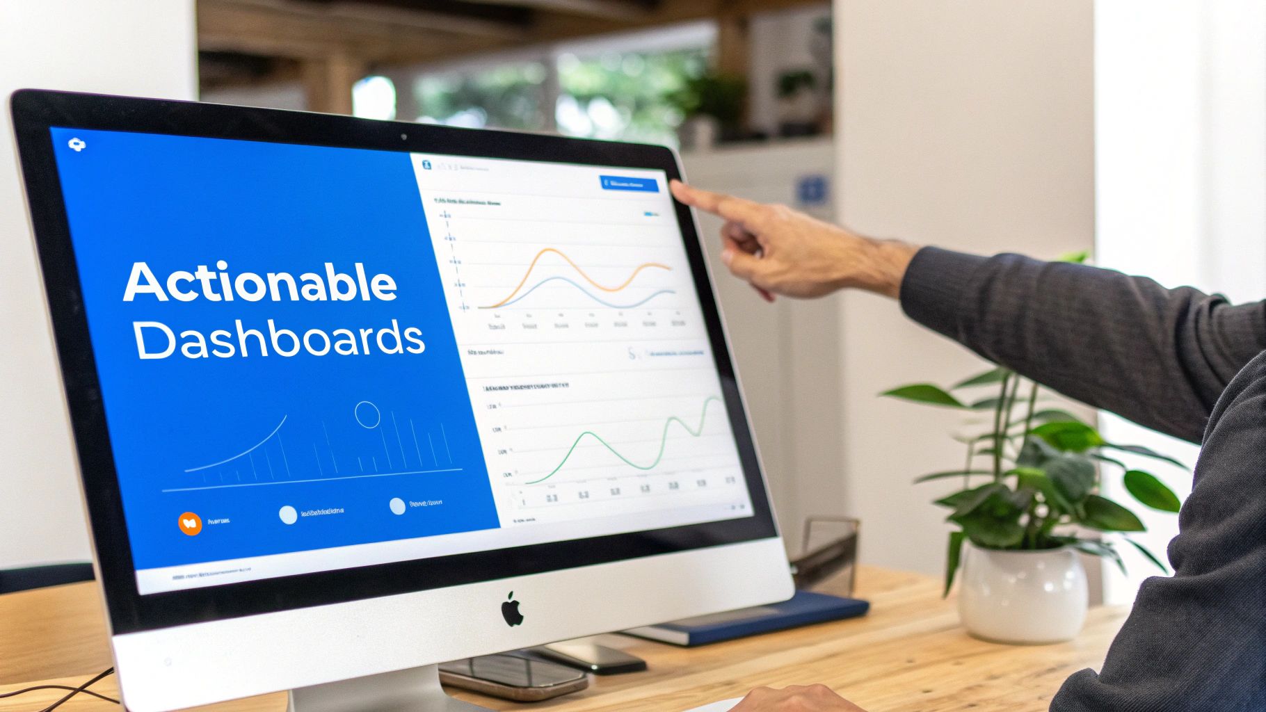 A person's hand points at an Apple desktop screen displaying actionable dashboards with graphs.