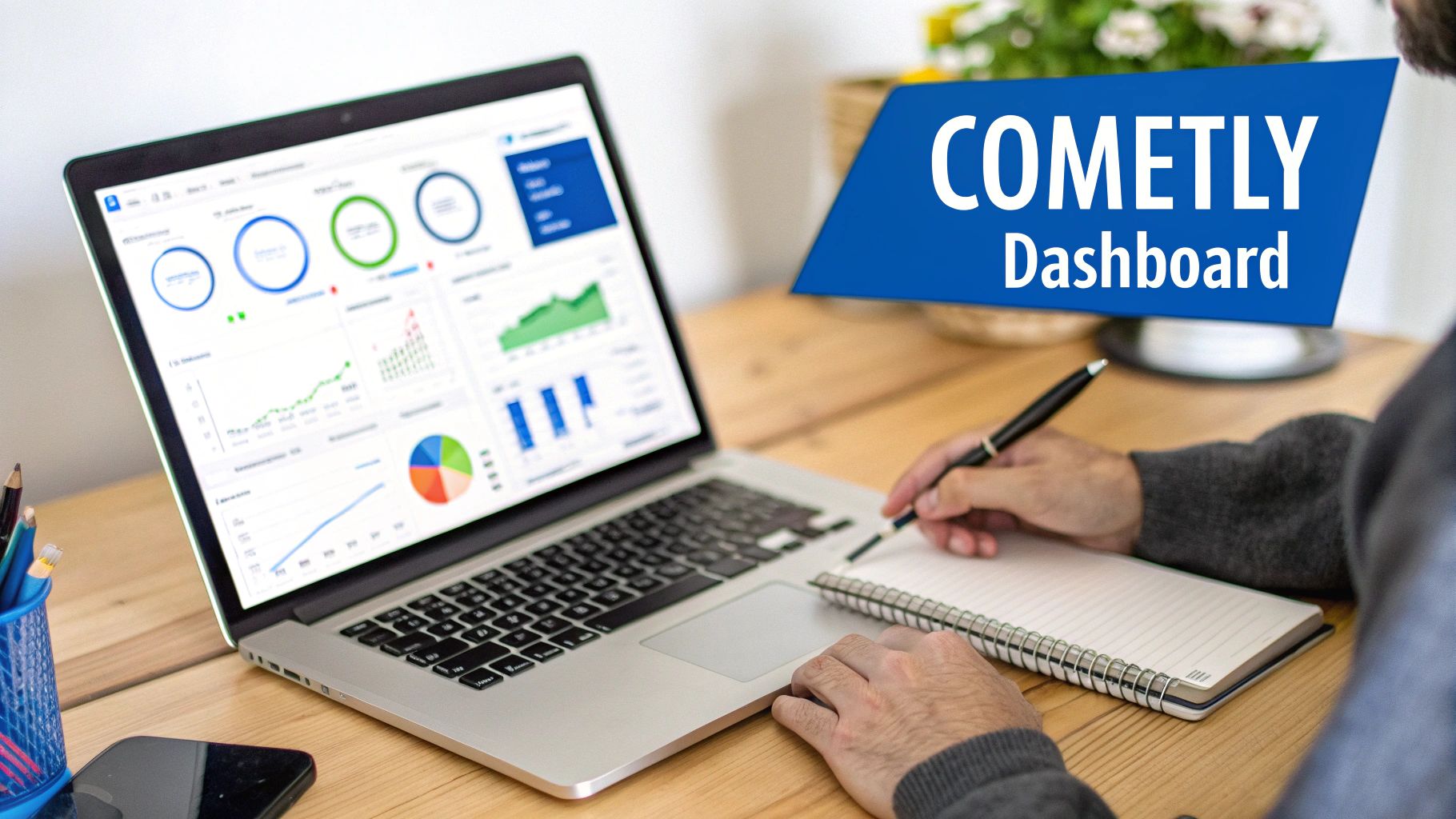 Person working on a laptop displaying a Comely data analytics dashboard and writing in a notebook.