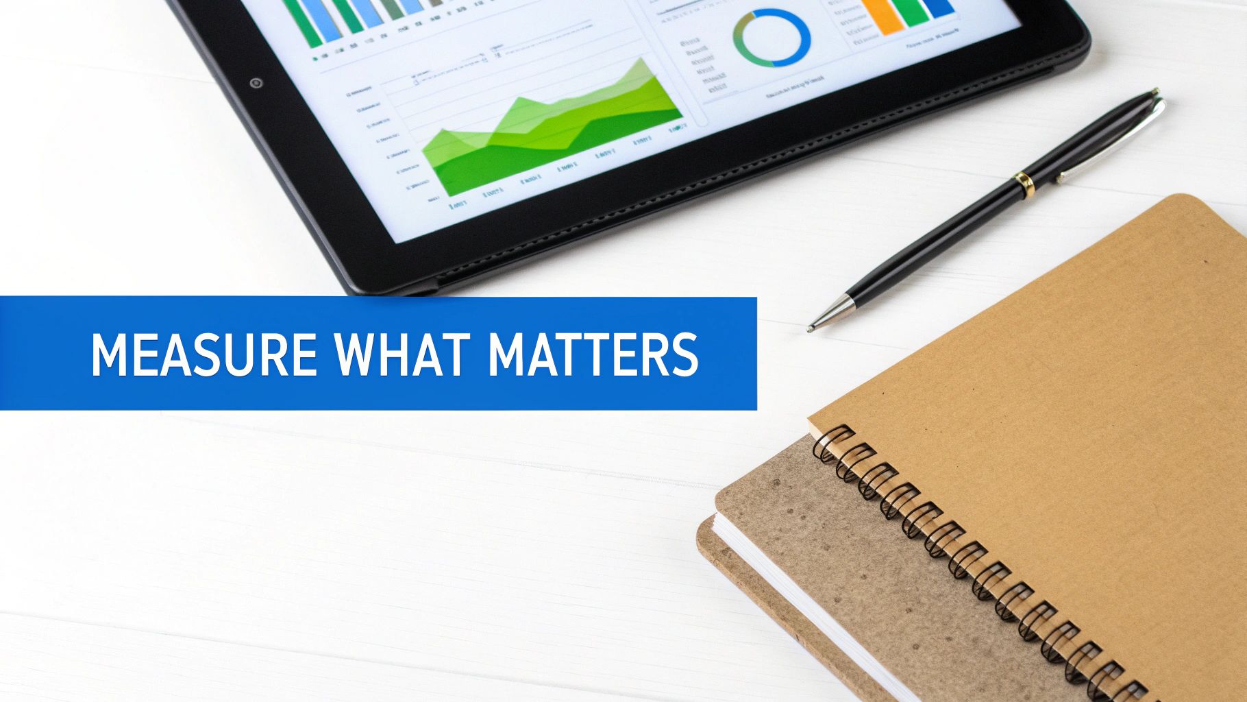 A tablet showing data visualizations, a pen, and notebooks on a desk, with the text 'MEASURE WHAT MATTERS'.