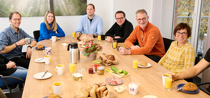 Mittagspause im Team: Mitarbeiter versammelt am Esstisch