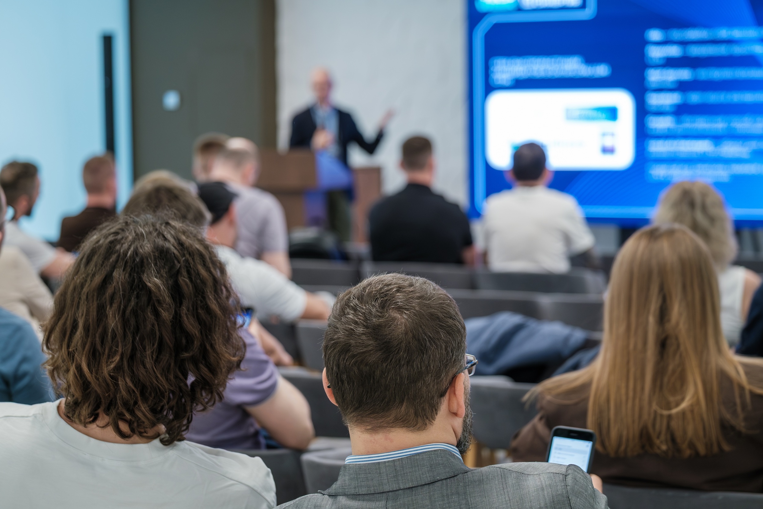 Business professionals attending a conference, illustrating employee training, continuous improvement, and quality management standards under Coastal Debt Resolve’s ISO 9001-certified processes.