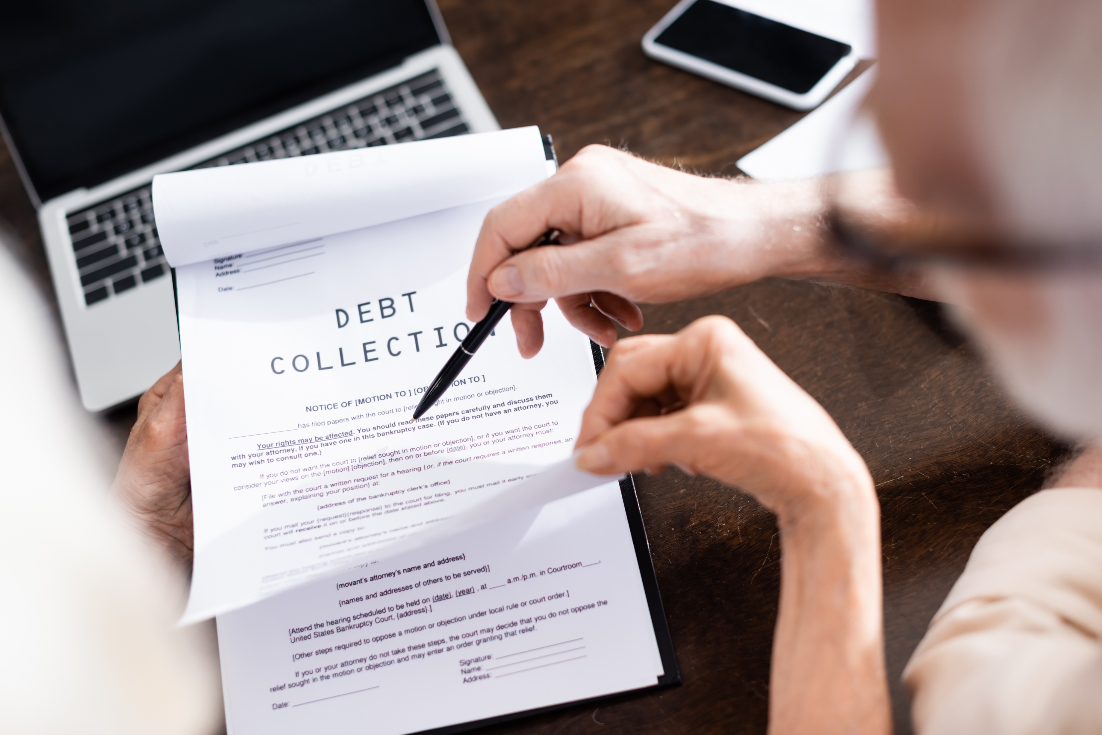A person reviews a debt collection notice at a desk, illustrating the collection rules covered in Coastal Debt Resolve’s California merchant cash advance guide.