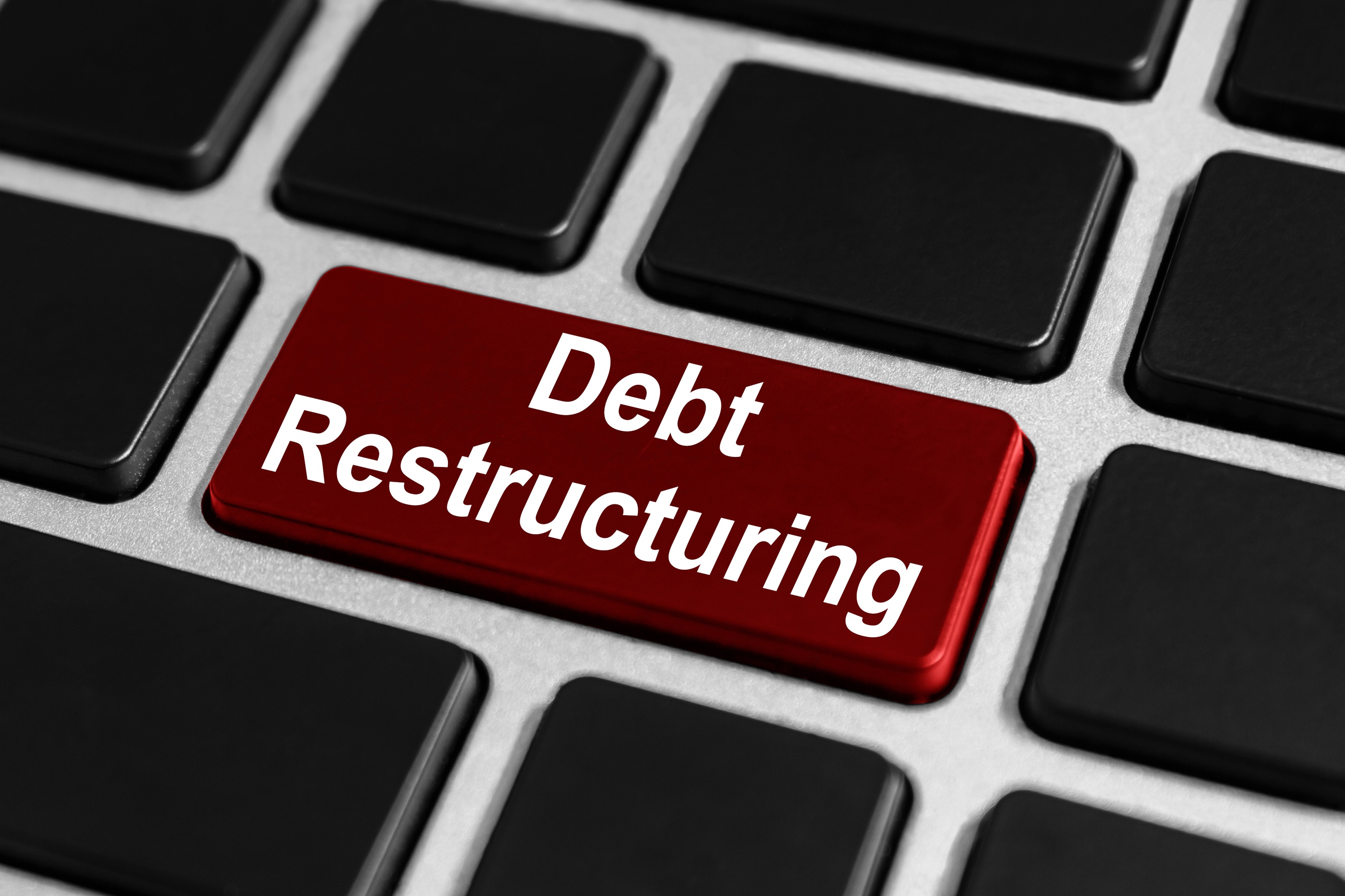 A close-up of a computer keyboard featuring a prominent red key labeled "Debt Restructuring," highlighting one of the primary out-of-court settlement services provided by Coastal Debt Resolve to help businesses manage MCA debt.