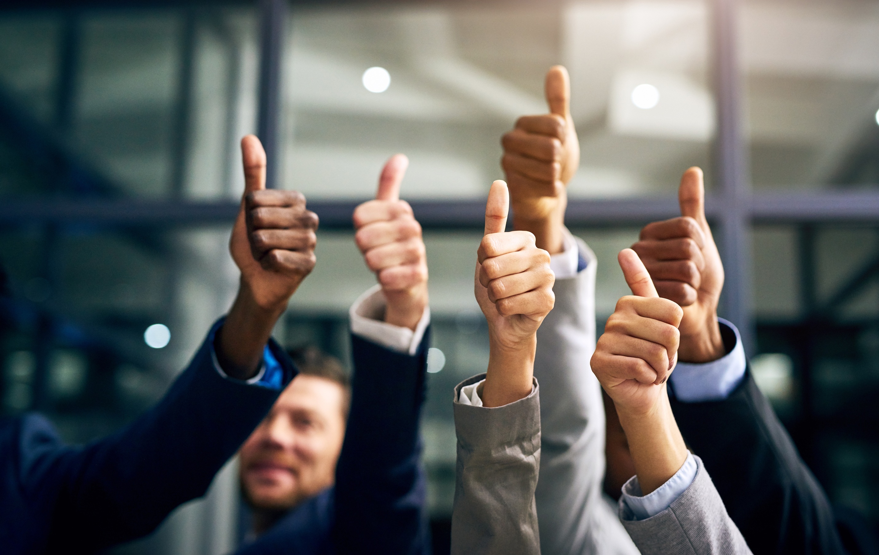 A diverse group of business professionals raising their hands in a thumbs-up gesture, symbolizing the trust, transparent success, and reputation Coastal Debt Resolve has built in the commercial debt relief industry.