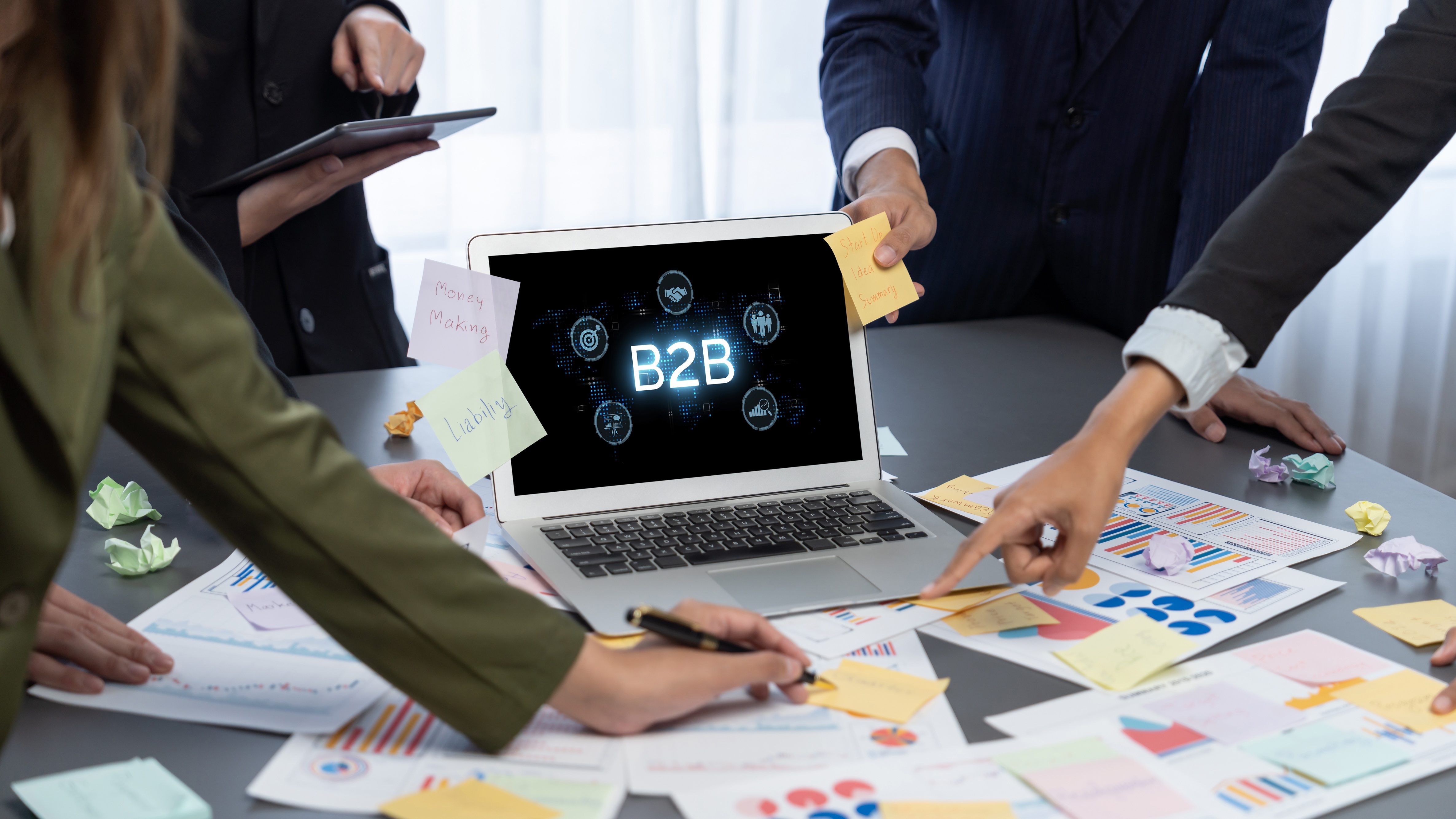 Business professionals reviewing charts around a B2B laptop, illustrating Coastal Debt Resolve’s commercial debt restructuring services.