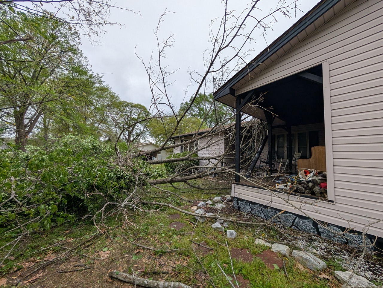 Storm-damaged tree branches leaning against house porch in Central Arkansas neighborhood
