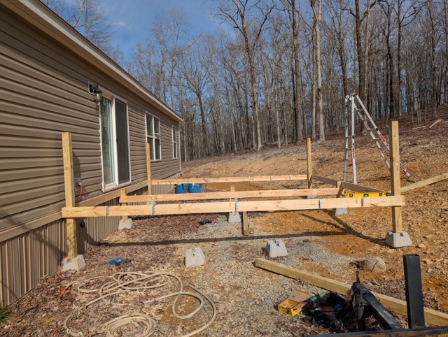 Wooden deck construction in progress behind house with tools and supplies visible