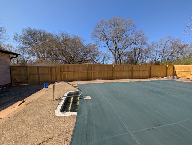 Covered swimming pool next to newly constructed wooden privacy fence