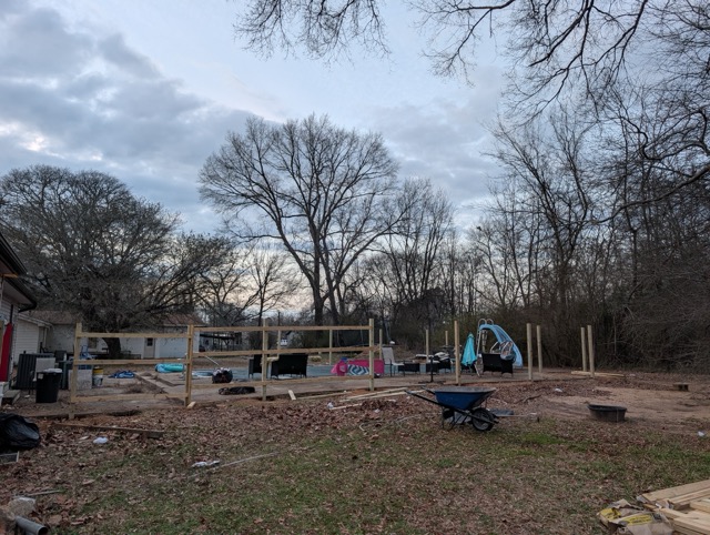 Construction site with playground in background and wooden posts installed for new deck