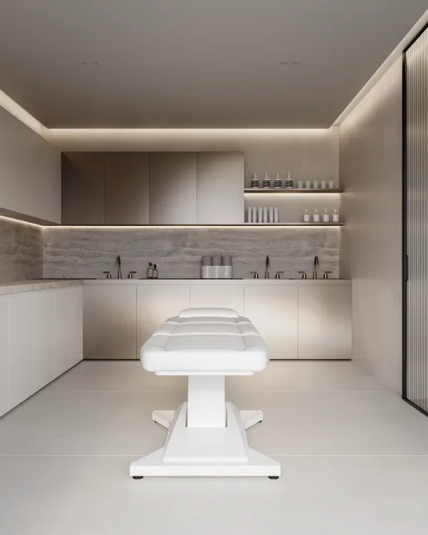 Modern minimalist spa treatment room with a white massage table, sleek cabinetry, and soft lighting.