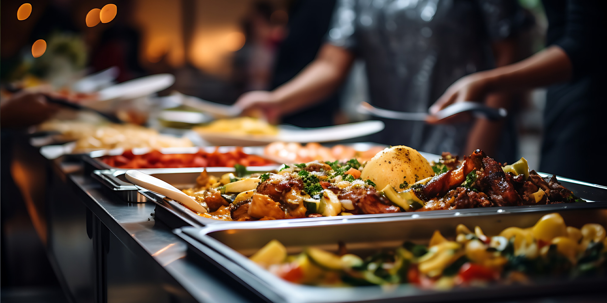 catering trays with large amounts of food. people serving food in the background