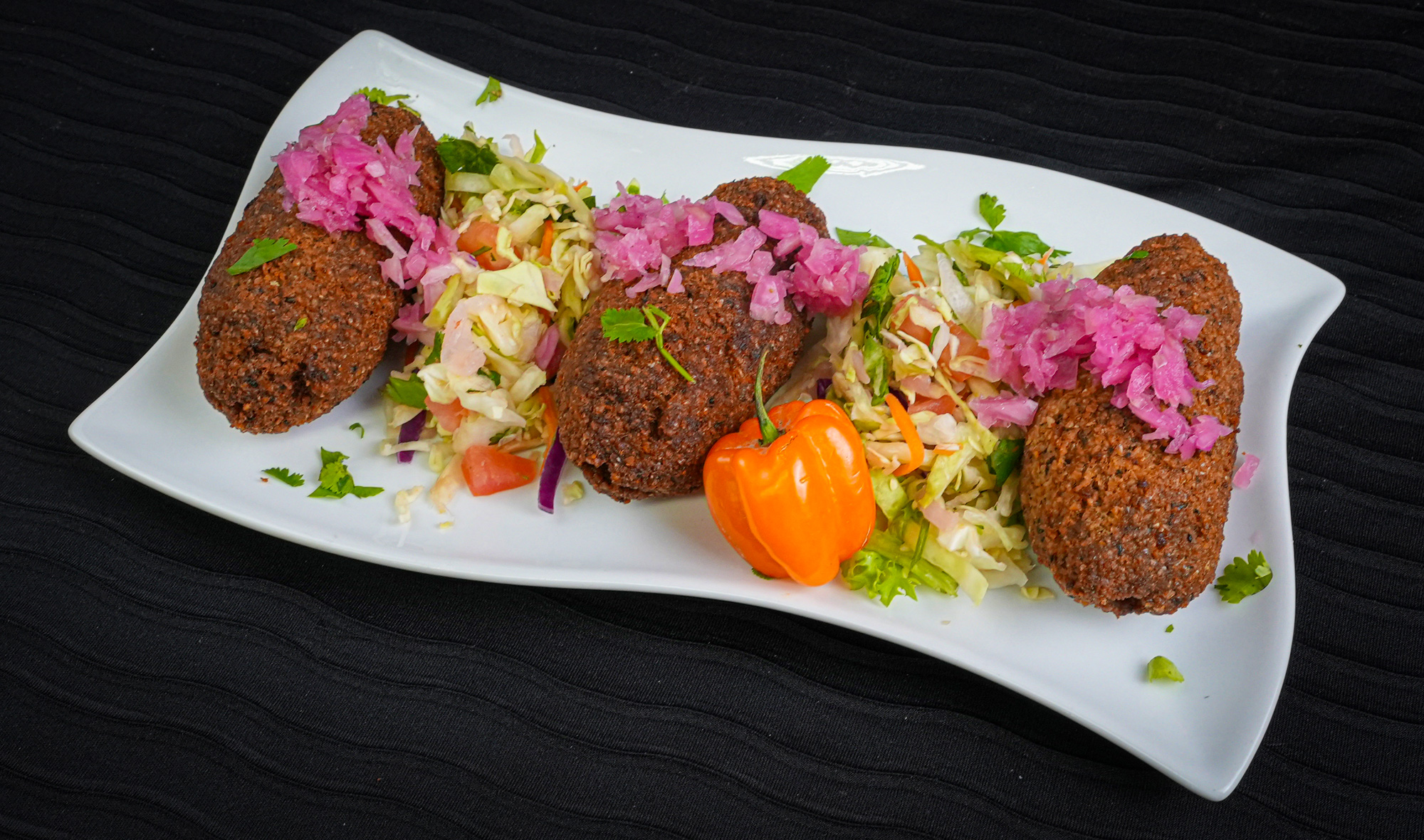 Deep fried Lebanese style meat ball with pickled purple fermented onions and orange pepper 