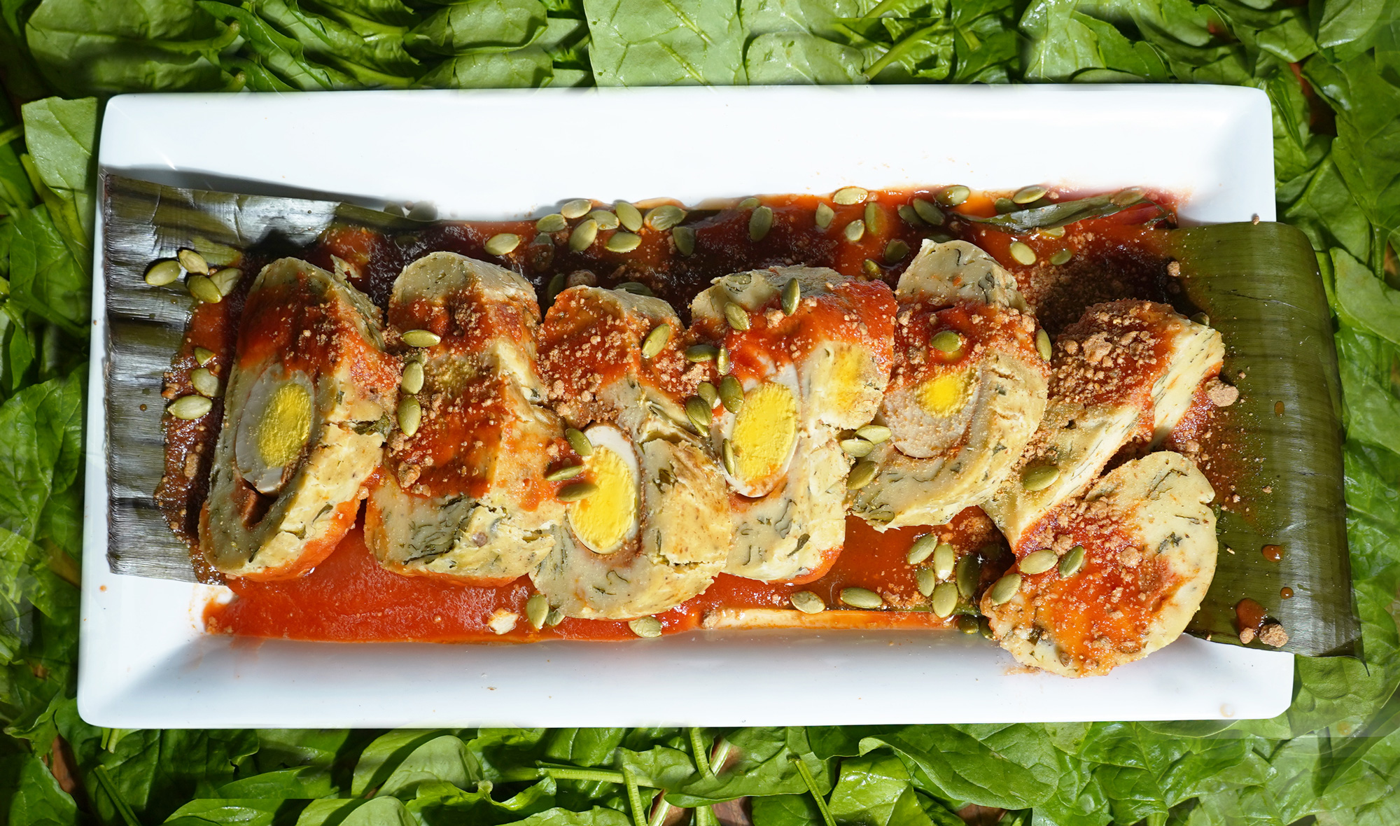 steamed tamale with hard boiled egg inside. scattered with pumpkin seeds