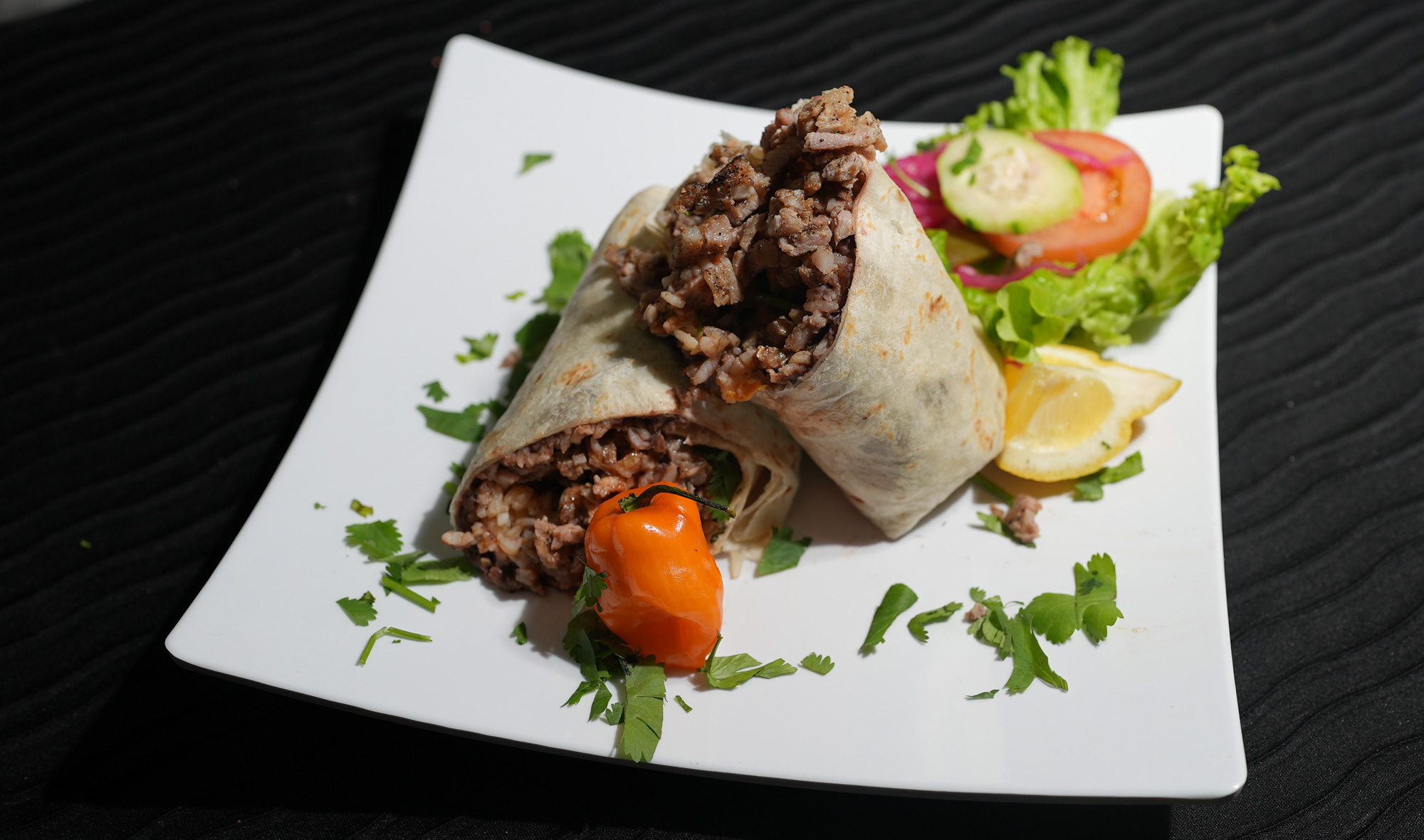 burrito with rice and meat with a side of salad