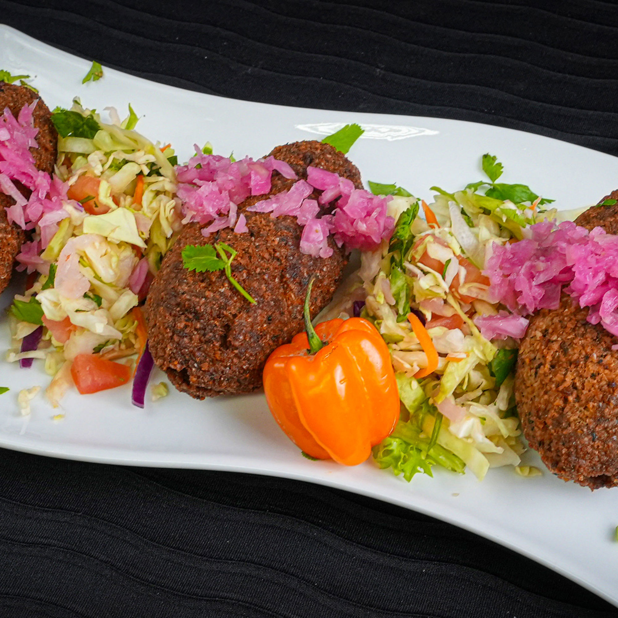 Deep fried Lebanese style meat ball with pickled purple fermented onions and orange pepper 
