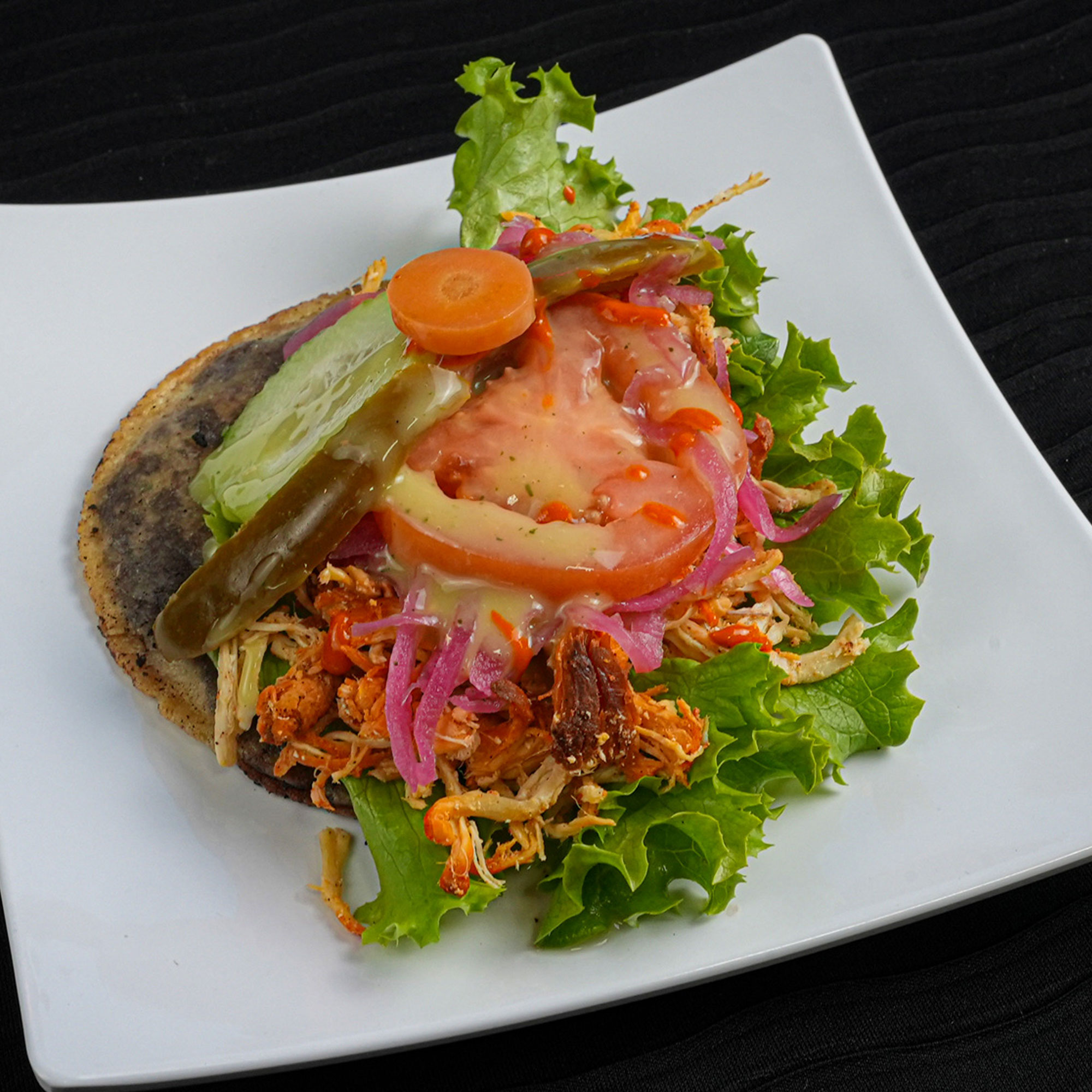 Handmade tortilla filled with pureed black beans, fried and then topped with lettuce, tomato, cucumber, pickle onions, avocado,