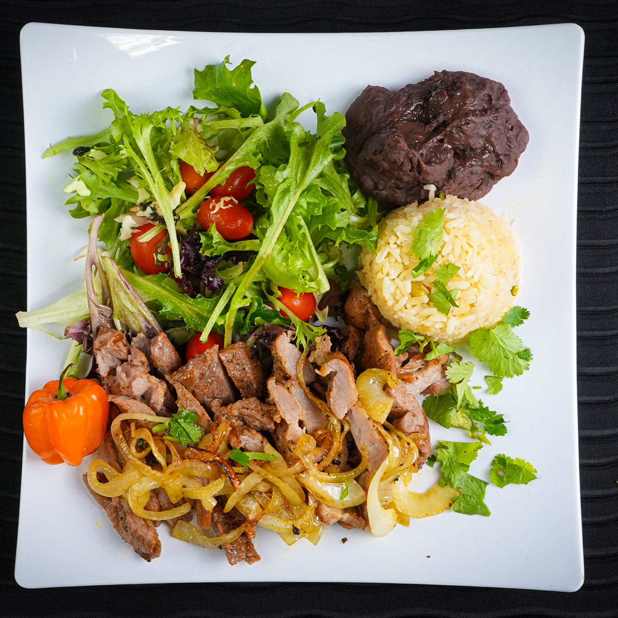 Strips of Meat with caramelized onions, beans, rice, and salad