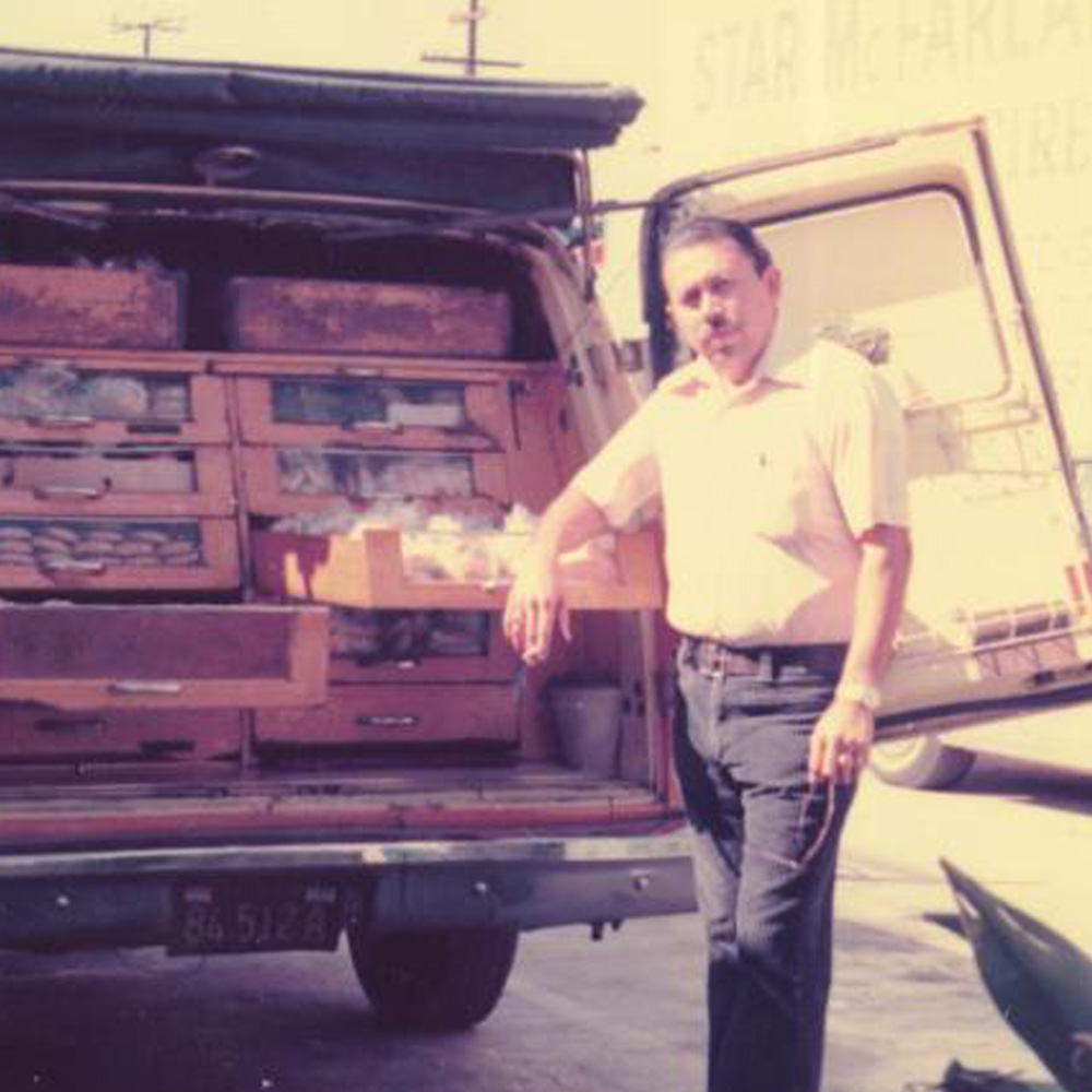 man standing in front of a van filled with bread