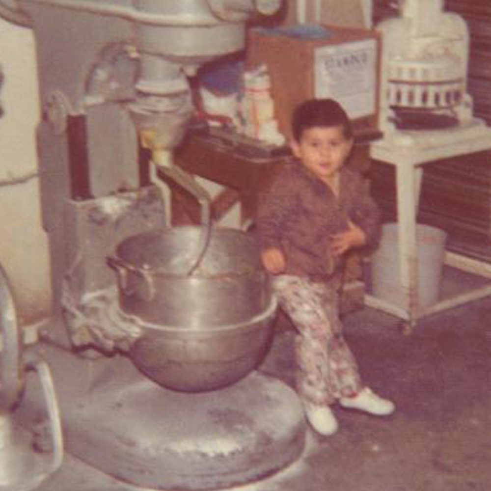 baby standing next to a large dough mixer