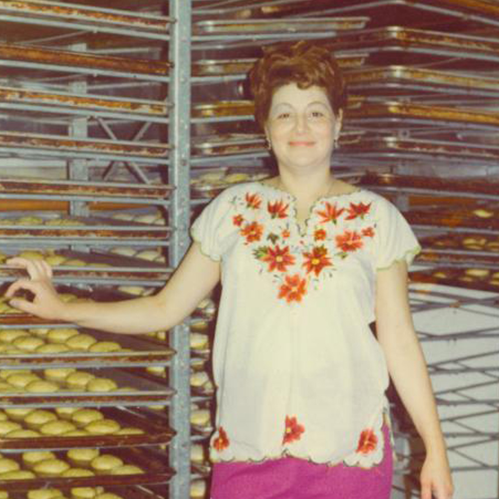 woman standing in front of trays of bread