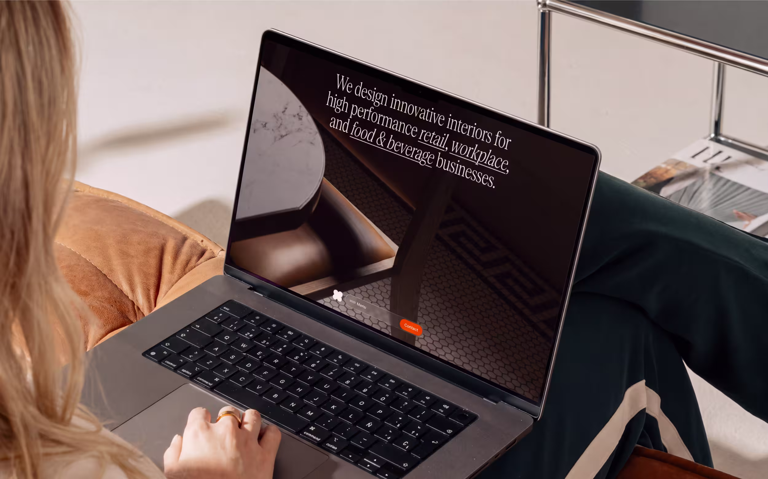A woman sat on a couch with a laptop on her lap, browsing the Studio X website
