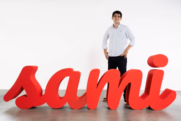 Logo da SAMI à frente e Vitor Asseituno ao fundo de pé.