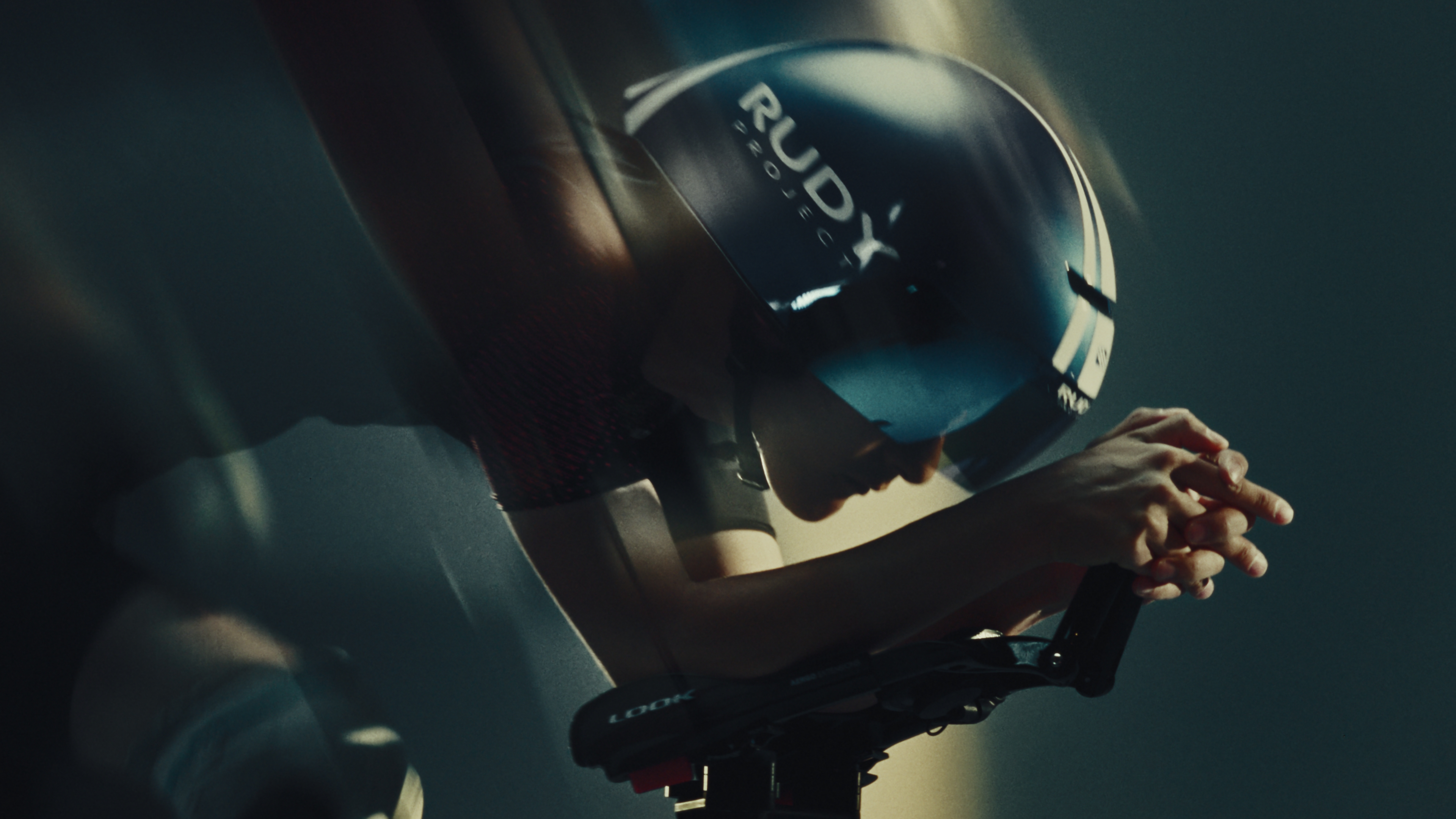 Close view of a cyclist in a Rudy Project time trial helmet, hands clasped over the aero bars