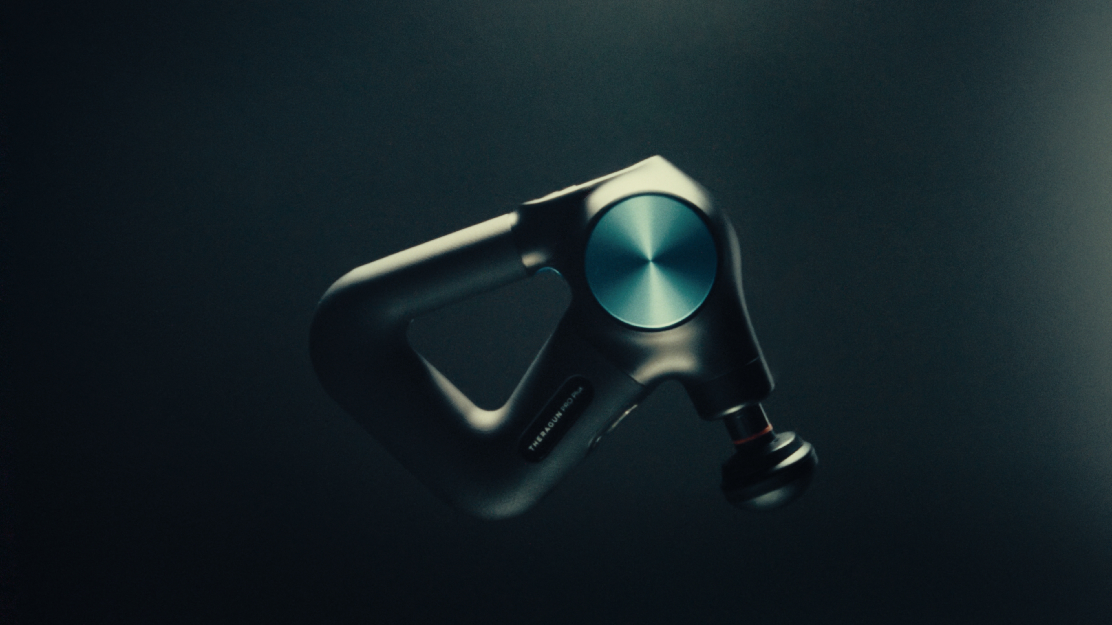 Theragun Pro Plus percussive therapy device floating against a dark background
